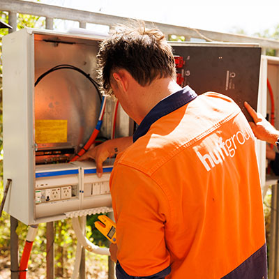 A man in an orange shirt repairs a power meter, representing Huffgroup electrical fit outs
