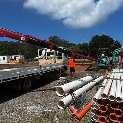 A truck is parked next to construction pipes, representing Huff Group's construction delivery services