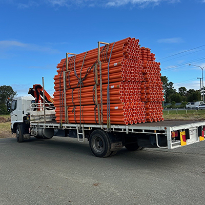 A truck from Huff Group transports a large stack of pipes for construction delivery services