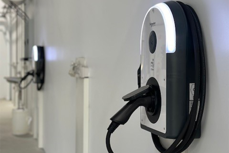 Wall-mounted electric charger with an indicator light, branded by Huff Group for service and maintenance use